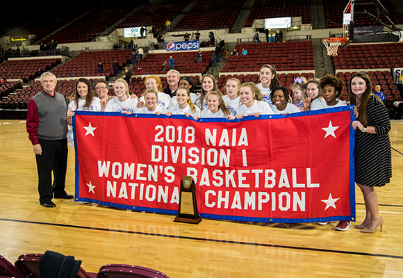 FHU Lady Lions pose with 2018 NAIA national champion banner.
