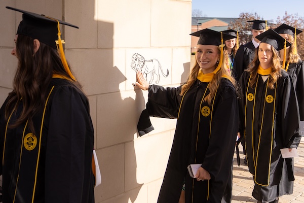 FHU December graduates touch the lion during the walk to Dryden Auditorium.