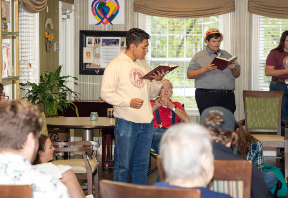 Male FHU student standing and leading the group at Southern Oaks in song