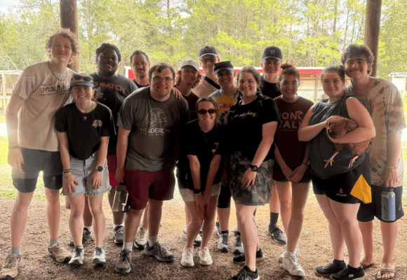 Group of FHU students under a pole building