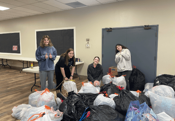 Four female FHU students posing with their hard work of bagging clothes