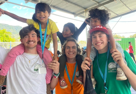 Three male FHU Students posing with three kids on their shoulders