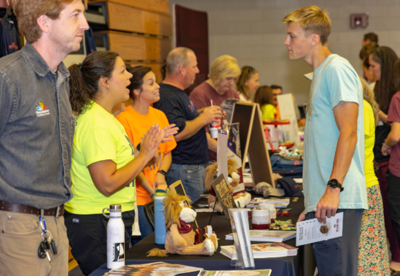 Welcome Home photo of inside the Brewer Sports System of local vendors talking to new students.