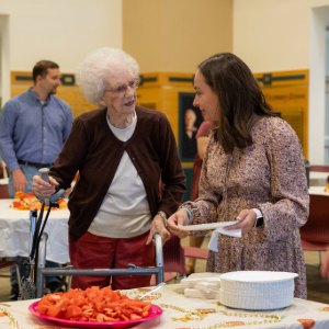 student getting plate of food for older lady at the Servants Day tea party in brown kopel business center