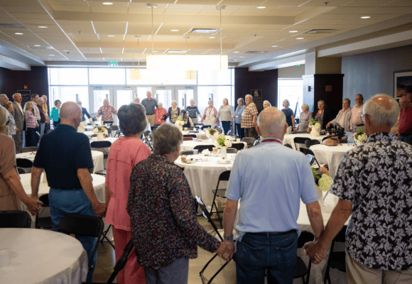Golden Year reunion group of people holding hands in a prayer ring