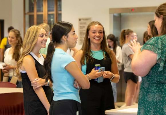 Three female students talk with guest speaker following Prescription for Success event