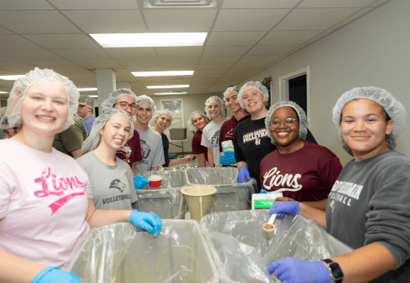 Group of male and female students forming an assembly line for food packing