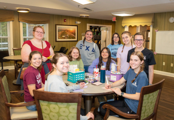 Female students gathered around a table at southern oaks with markers and paper