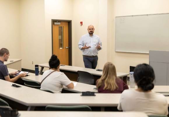 Man speaks to students in a classroom setting.