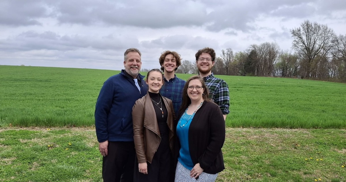 Family of five stand for a group picture.