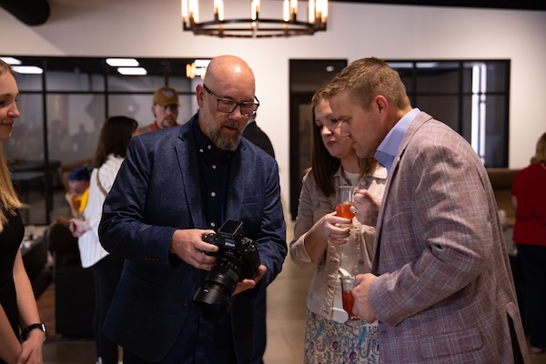 FHU professor Jud Davis shows a few photos to President Keith Harris and First Lady Lindsey during the reception.