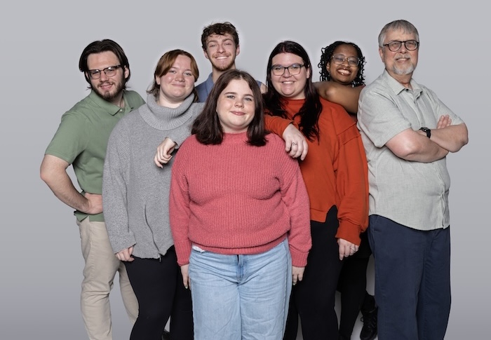 Cast members of "The Fabulist" stand in front of a grey background.