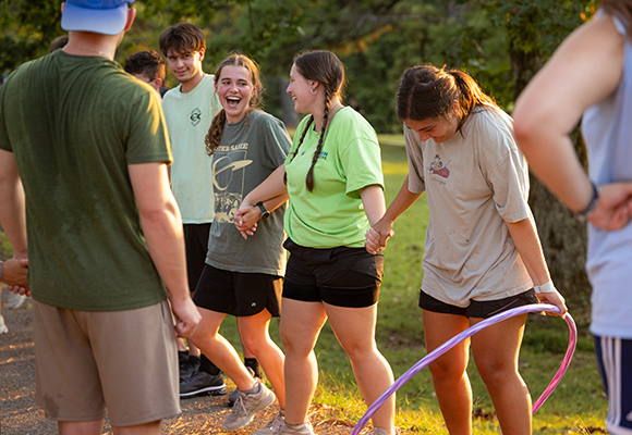 interface students hold hands while playing a game outside