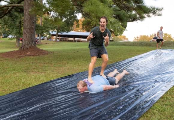 male student surfing down slip-n-slide