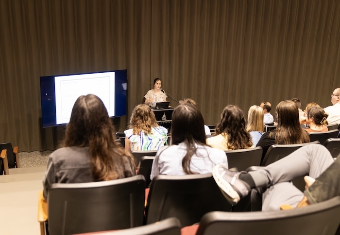 An FHU student presents her Scholars' Day research to a crowd of students and faculty in Dryden Auditorium.