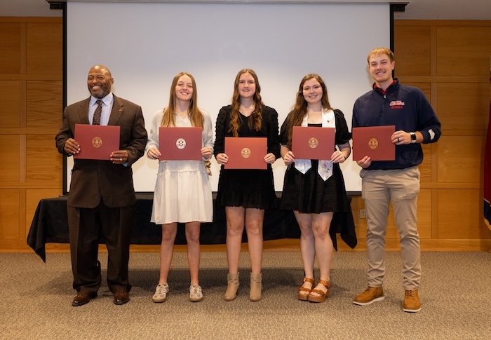 Five education graduates hold diplomas after their pinning ceremony