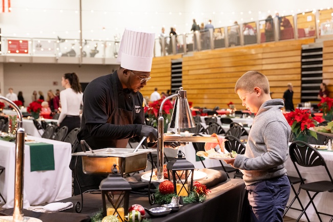 Benefit Dinner cook serves child with a plate
