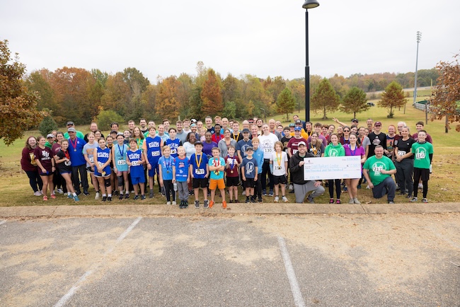 Participants in FHU's 5K for the Children pose with donation check