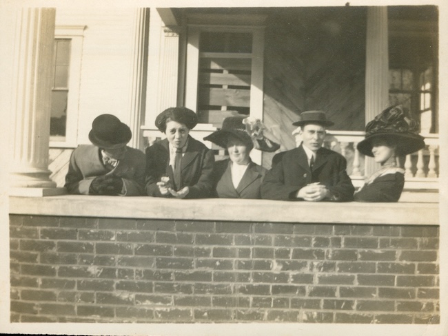 Five individuals stand beside the Joy Simon McDaniel House in the early 1900s.