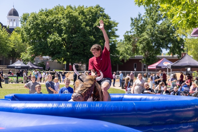 Student rides a mechanical bull in the FHU commons.